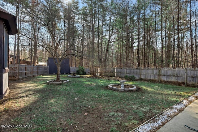 view of yard with a storage unit, an outbuilding, and a fenced backyard