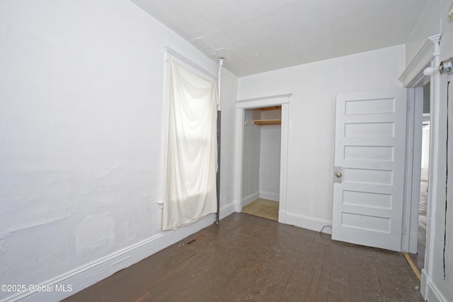 unfurnished bedroom with baseboards and dark wood-style floors