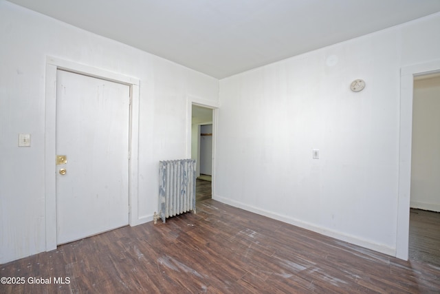 unfurnished bedroom with a closet, radiator heating unit, and wood finished floors