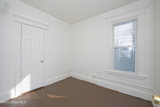 unfurnished room with baseboards and dark wood-style floors
