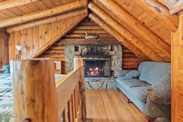 sitting room with wooden ceiling, a stone fireplace, rustic walls, vaulted ceiling with beams, and wood finished floors