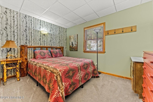 bedroom with light carpet, a paneled ceiling, and baseboards