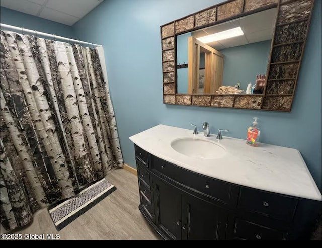 bathroom with a shower with shower curtain, a drop ceiling, vanity, and wood finished floors