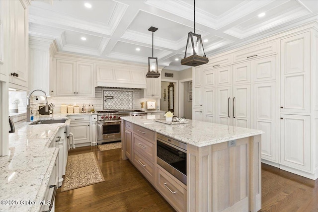 kitchen with light stone countertops, a sink, an island with sink, stainless steel appliances, and backsplash