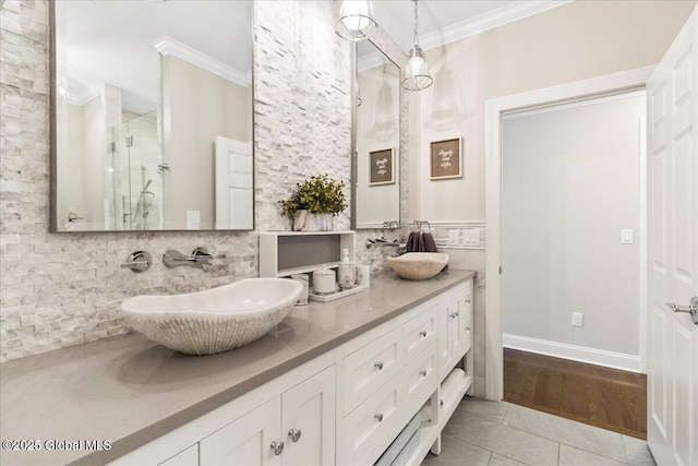 bathroom with double vanity, ornamental molding, a sink, and a shower stall