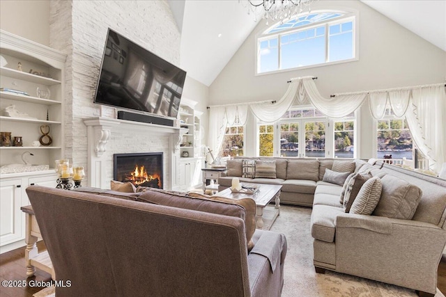 living room featuring built in features, a fireplace, a notable chandelier, and high vaulted ceiling
