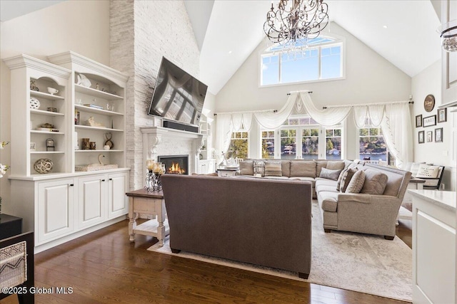 living area with high vaulted ceiling, dark wood-style flooring, a large fireplace, and a chandelier