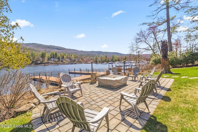 view of patio / terrace featuring a dock, a fire pit, and a water and mountain view