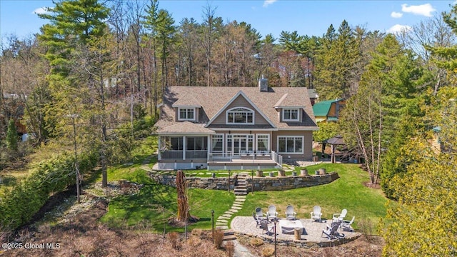 rear view of house featuring an outdoor fire pit, a sunroom, a deck, a lawn, and a patio