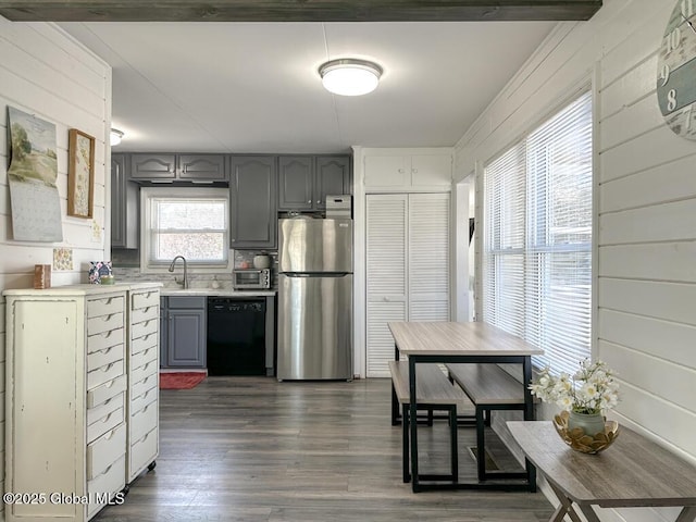 kitchen featuring black dishwasher, light countertops, gray cabinetry, freestanding refrigerator, and dark wood finished floors