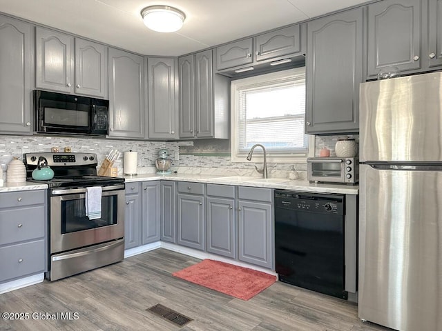 kitchen with a sink, tasteful backsplash, black appliances, a toaster, and gray cabinetry