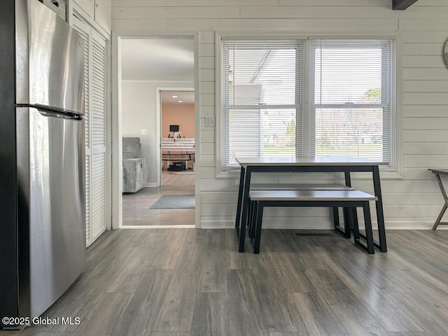 dining area with baseboards, wood finished floors, and wooden walls