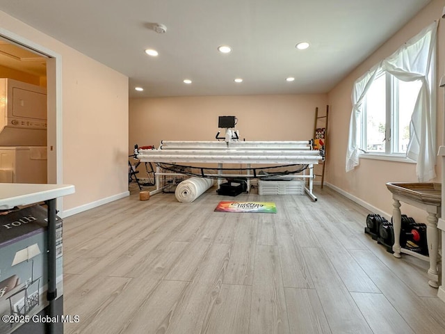 playroom featuring stacked washing maching and dryer, recessed lighting, light wood-style flooring, and baseboards