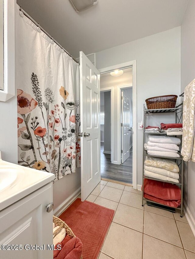 full bath with baseboards, a shower with shower curtain, tile patterned flooring, and vanity