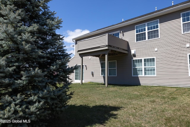 back of house featuring a lawn and a balcony