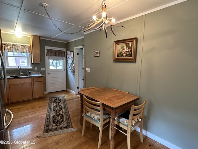 6325 Sunset Bay Rd, Dresden, NY 12841 - dining room featuring light wood-type flooring, crown molding, baseboards, and a notable chandelier
