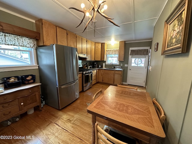 6325 Sunset Bay Rd, Dresden, NY 12841 - kitchen featuring brown cabinets, under cabinet range hood, an inviting chandelier, light wood-type flooring, and appliances with stainless steel finishes