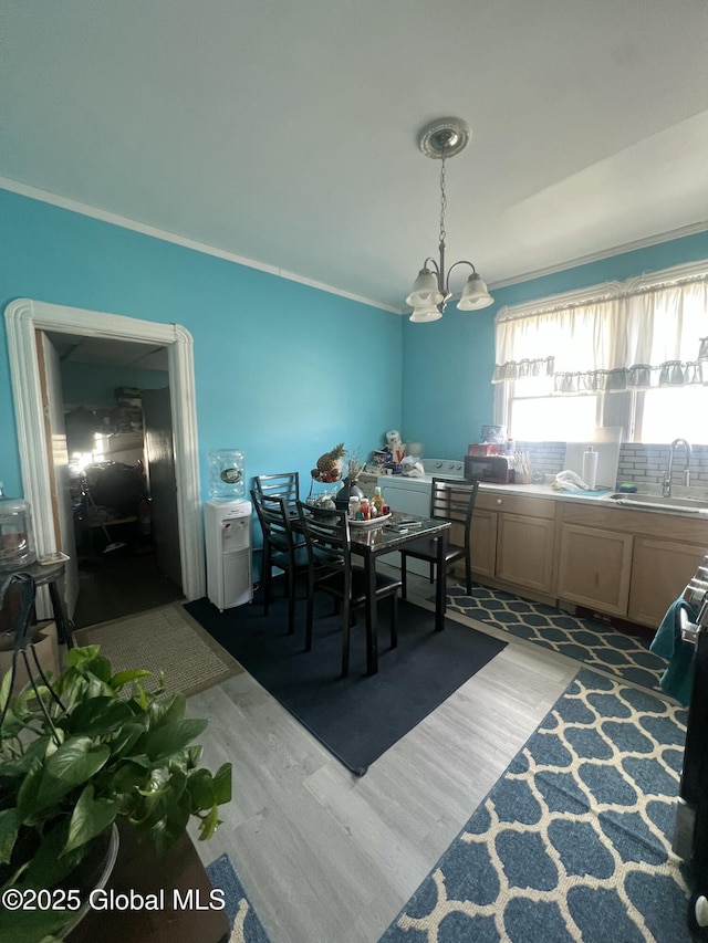 dining area featuring an inviting chandelier, ornamental molding, and light wood-type flooring