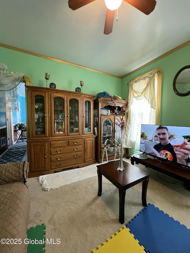 living room with ornamental molding, a ceiling fan, and carpet