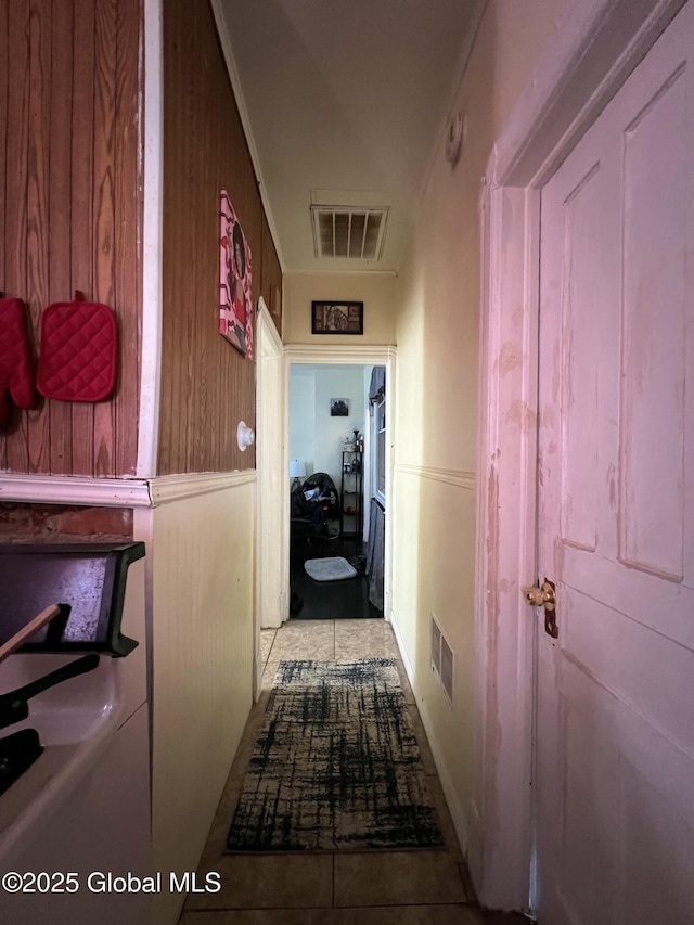hall with wooden walls, visible vents, and tile patterned flooring