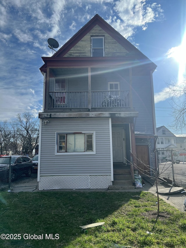 view of front of home featuring a front lawn, fence, and a balcony