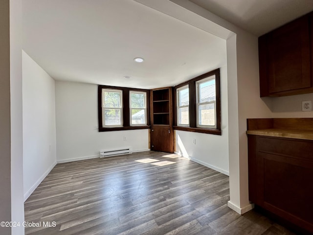 unfurnished dining area with dark wood-style flooring, baseboards, recessed lighting, built in shelves, and baseboard heating