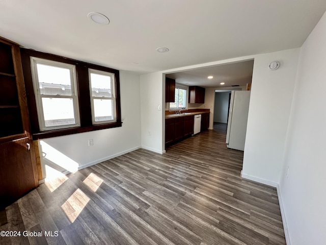 unfurnished living room with baseboards, a sink, dark wood-type flooring, and recessed lighting