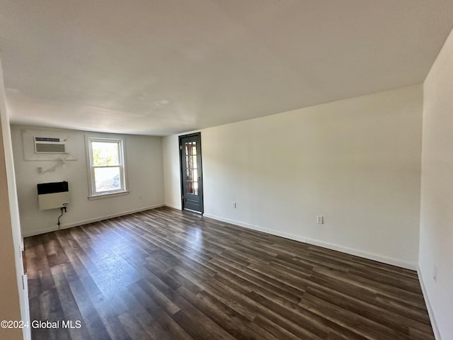 unfurnished living room with baseboards, heating unit, and dark wood-style floors