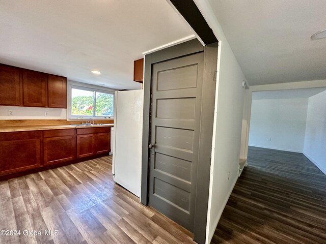kitchen with a sink, brown cabinets, light countertops, dark wood-style floors, and freestanding refrigerator