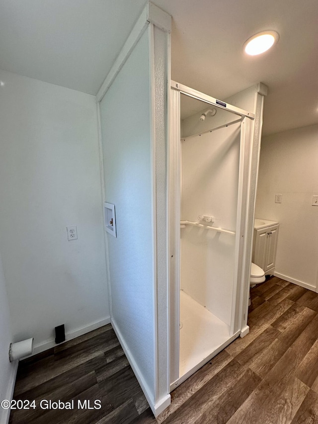 full bath with a shower stall, toilet, wood finished floors, and baseboards