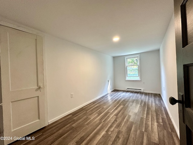 unfurnished living room featuring baseboards, baseboard heating, and dark wood-style floors