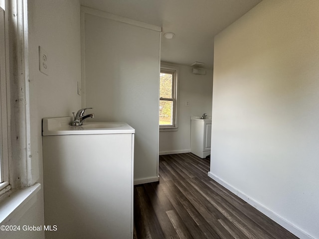 clothes washing area with baseboards, dark wood-style flooring, and a sink