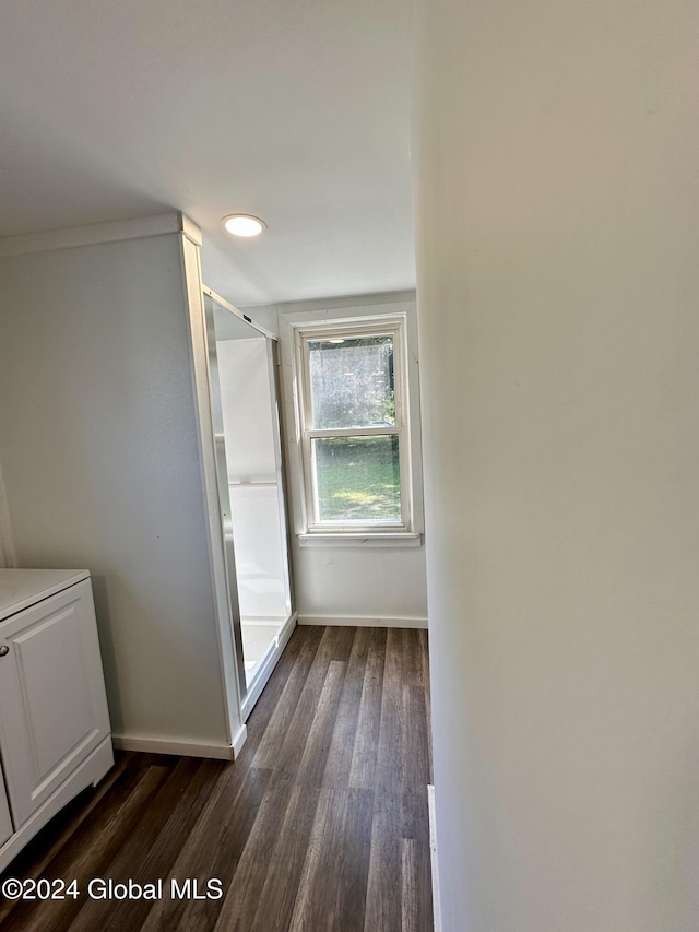 hallway with dark wood-type flooring and baseboards