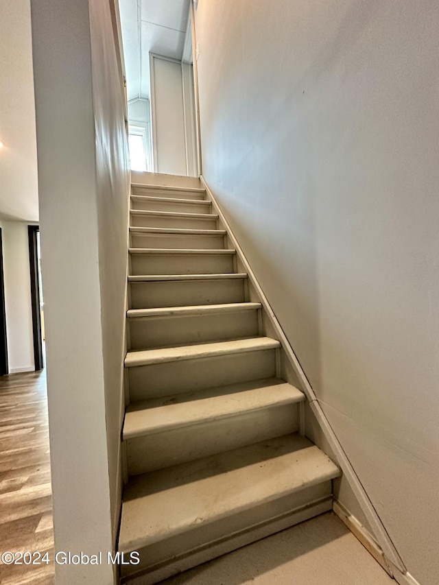 staircase with baseboards and wood finished floors
