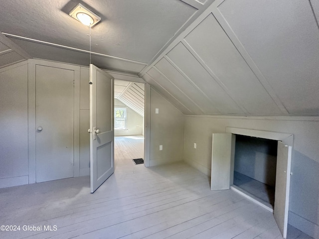 additional living space featuring lofted ceiling and light wood-style flooring