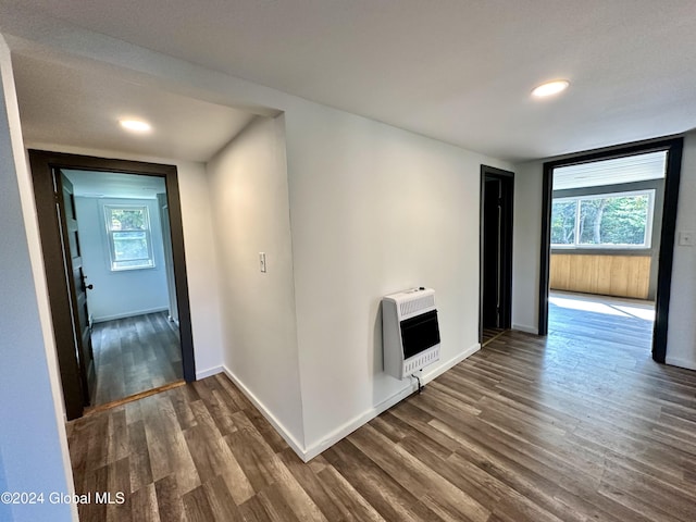 hall featuring plenty of natural light, heating unit, dark wood-style floors, and baseboards