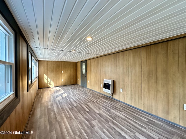 interior space with wooden ceiling, wood finished floors, heating unit, and wooden walls