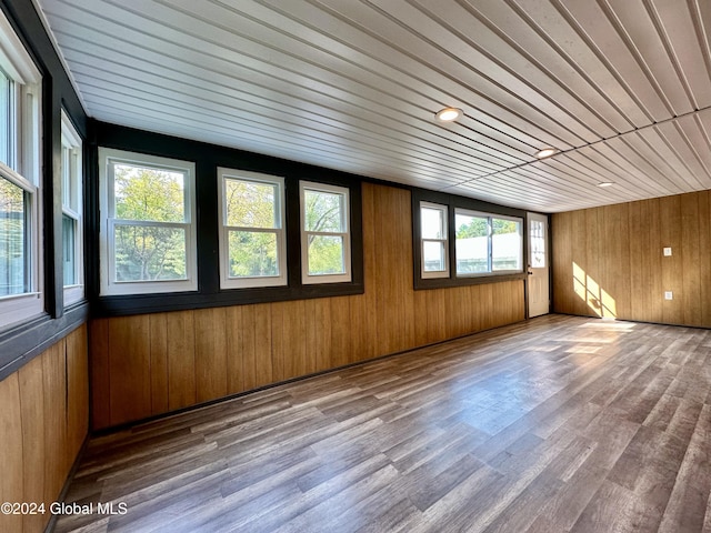 empty room with wooden walls, wood finished floors, and wooden ceiling