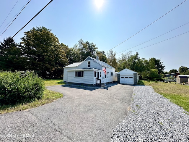 bungalow featuring a garage, an outbuilding, a chimney, and driveway