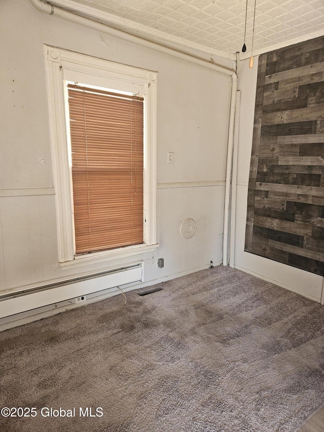 235 5th Ave, Troy, NY 12180 - empty room featuring a baseboard heating unit, carpet flooring, wooden walls, and wainscoting