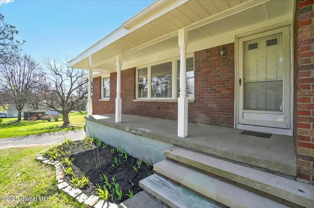 doorway to property with brick siding and a porch