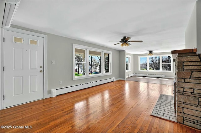 unfurnished living room featuring hardwood / wood-style flooring, a baseboard radiator, baseboards, and ceiling fan