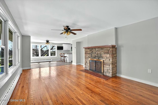 unfurnished living room with light wood-style flooring, a ceiling fan, and baseboard heating