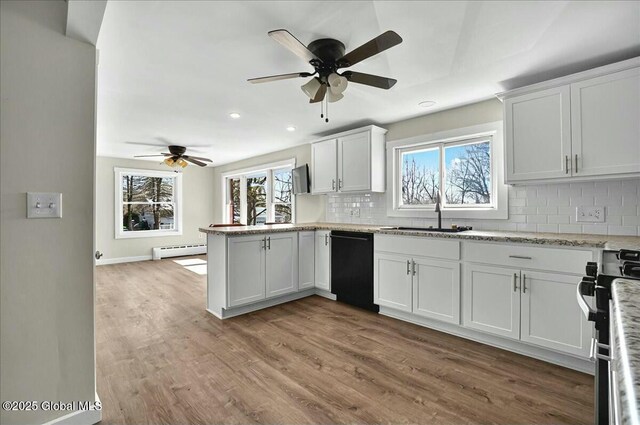 kitchen featuring a ceiling fan, a sink, a baseboard radiator, and black dishwasher