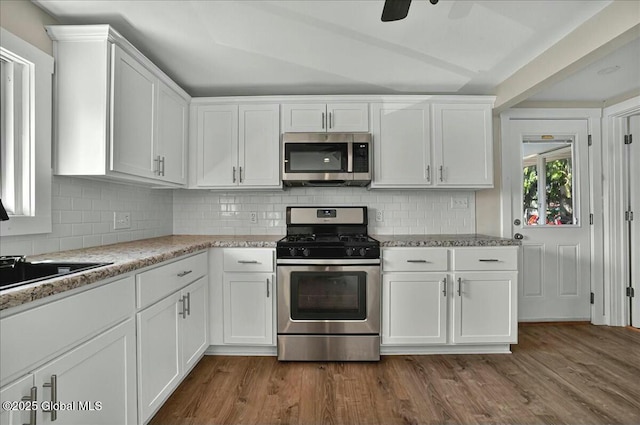 kitchen with white cabinets, decorative backsplash, appliances with stainless steel finishes, and light stone countertops