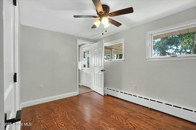unfurnished room with a baseboard radiator, baseboards, a ceiling fan, and wood finished floors