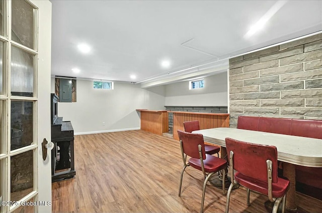 dining area featuring baseboards, wood finished floors, a bar, and a healthy amount of sunlight