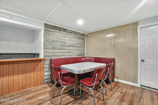 dining room featuring wooden walls, wood finished floors, and a bar