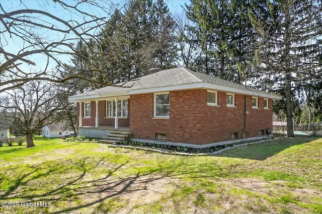 back of house with brick siding and a yard