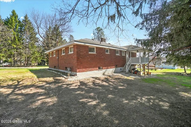 rear view of house with a chimney, brick siding, a deck, and stairway